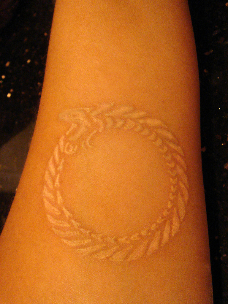 White Ink Ouroboros Tattoo On Left Forearm