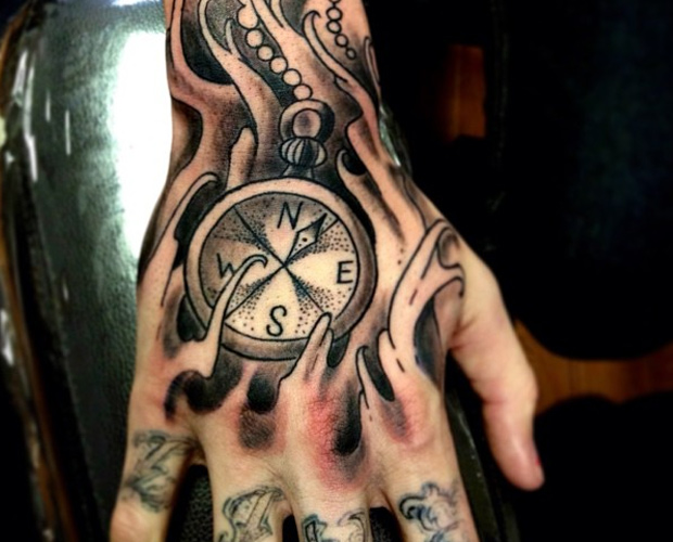 Compass with chain & ripped skin tattoo on back hand