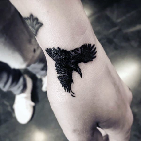 Small Black Flying Crow Tattoo On Hand