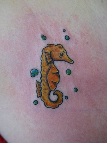 Yellow Ink Seahorse Tattoo On Upper Back